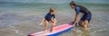 Father or instructor teaching his 5 year old son how to surf in the sea on vacation or holiday. Travel and sports with