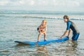 Father or instructor teaching his 4 year old son how to surf in the sea on vacation or holiday. Travel and sports with