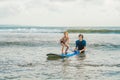 Father or instructor teaching his 4 year old son how to surf in the sea on vacation or holiday. Travel and sports with