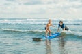 Father or instructor teaching his 4 year old son how to surf in the sea on vacation or holiday. Travel and sports with