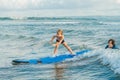 Father or instructor teaching his 4 year old son how to surf in the sea on vacation or holiday. Travel and sports with