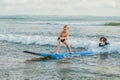 Father or instructor teaching his 4 year old son how to surf in the sea on vacation or holiday. Travel and sports with