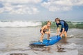 Father or instructor teaching his 4 year old son how to surf in Royalty Free Stock Photo