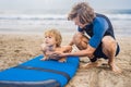 Father or instructor teaching his 4 year old son how to surf in Royalty Free Stock Photo