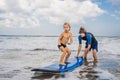 Father or instructor teaching his 4 year old son how to surf in Royalty Free Stock Photo