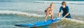 Father or instructor teaching his 4 year old son how to surf in the sea on vacation or holiday. Travel and sports with Royalty Free Stock Photo