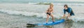 Father or instructor teaching his 4 year old son how to surf in the sea on vacation or holiday. Travel and sports with