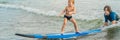 Father or instructor teaching his 4 year old son how to surf in the sea on vacation or holiday. Travel and sports with