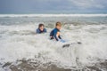 Father or instructor teaching his 5 year old son how to surf in the sea on vacation or holiday. Travel and sports with