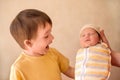 Little toddler boy meets infant baby sister for first time. Elder brother with funny face looking at newborn relative Royalty Free Stock Photo