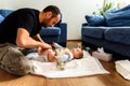 A father involved in taking care of his children by changing his daughter`s dirty diaper. Concept of work family conciliation Royalty Free Stock Photo