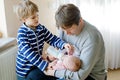 Father and kid boy feeding newborn baby daughter with milk in nursing bottle Royalty Free Stock Photo