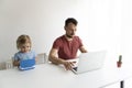 Father and kid work at laptops