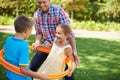 Father, kids and hula hoop in park for playing, child development and motor skills outdoor. Children, son and daughter