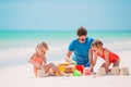 Father and kids making sand castle at tropical beach. Family playing with beach toys Royalty Free Stock Photo