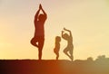 Father with kids silhouettes doing yoga at sunset Royalty Free Stock Photo