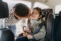 Father kisses his toddler daughter buckled into her baby car seat Royalty Free Stock Photo