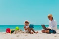 Father with laptop and cute daughter with touch pad on beach Royalty Free Stock Photo