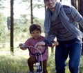 Father learning his son to ride on bicycle outside