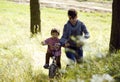 Father learning his son to ride on bicycle outside, real happy family in summer forest enjoing nature