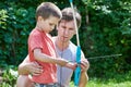 Father is learning his son to shoot from bow