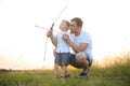 Father is learning his son to shoot from bow in sunny summer day.