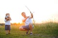 Father is learning his son to shoot from bow in sunny summer day.