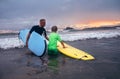 Father learning his son to surf at sunset time