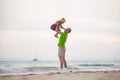 Father lift up daughter on hands on sunset ocean beach with yacht on back