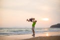 Father lift up daughter on hands on sunset ocean beach with yacht on back