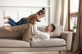 Father lift up daughter while lying on couch play together