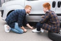 father lifting car with floor jack for changing tire son looking Royalty Free Stock Photo