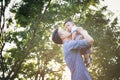 Father lifting son in hand and pretending to wheel with pleasure on blur background at garden, Lifestyle and Family Concepts