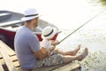 Father with little son fishing on the shore of the river Royalty Free Stock Photo