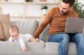 Father With Little Baby Using Laptop Working Remotely From Home Royalty Free Stock Photo