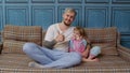 Father and little child daughter kid in pajamas sit on couch in room smiling, showing thumbs up Royalty Free Stock Photo