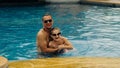 The father with little daughter have fun in the pool. Dad plays with the child. The family enjoy summer vacation in a Royalty Free Stock Photo