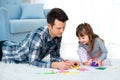 Father and little daughter having quality family time together at home. dad with girl lying on warm floor drawing with colorful Royalty Free Stock Photo