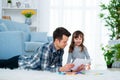 Father and little daughter having quality family time together at home. dad with girl lying on warm floor drawing with colorful Royalty Free Stock Photo