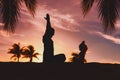 Father and little daughter silhouettes exercise at sunset beach, family doing yoga Royalty Free Stock Photo