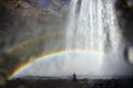 Father and little daughter at Skogafoss waterfall under the rainbow, Iceland