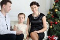 Father, little daughter and smiling mother sit on sofa