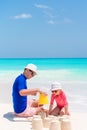 Father and little daughters making sand castle at tropical beach Royalty Free Stock Photo