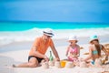 Father and little daughters making sand castle at tropical beach Royalty Free Stock Photo