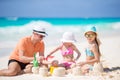 Father and little daughters making sand castle at tropical beach Royalty Free Stock Photo