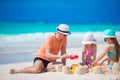 Father and little daughters making sand castle at tropical beach Royalty Free Stock Photo