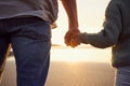 Father and little girl holding hands while watching the sunset together at the beach. Dad and young daughter showing Royalty Free Stock Photo