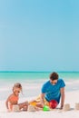 Father and kids making sand castle at tropical beach. Family playing with beach toys Royalty Free Stock Photo