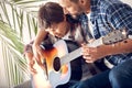 Father and little son at home sitting on sofa dad hugging boy playing guitar together joyful close-up Royalty Free Stock Photo