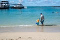 Father and little son playing in the gentle blue ocean waves at the sandy beach